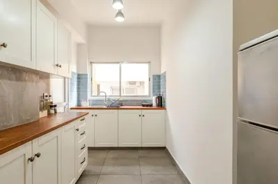 a kitchen with white cabinets and a stainless steel refrigerator at Cosy 2-Bedroom Apartment, 10 Minutes from the Beach in Larnaka