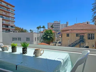 a table on a balcony with a view of a city at Albert's Apartment Center 203B in Larnaka