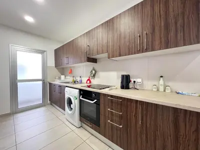 a kitchen with wooden cabinets and a washing machine at Albert's Apartment Center 203B in Larnaka