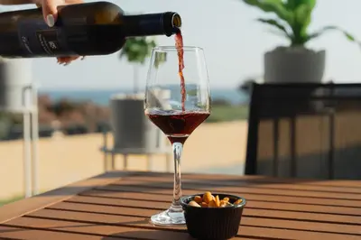 a person pouring wine into a glass on a table at Infinity Residences in Zygi