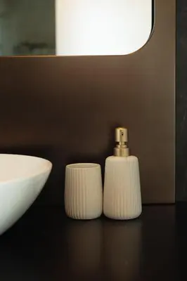 two white soap dispensers sitting on a counter next to a sink at Infinity Residences in Zygi