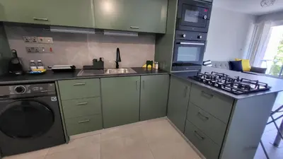 a kitchen with green cabinets and a washing machine at Hanapartment 3 bed Ayia NAPA in Ayia Napa