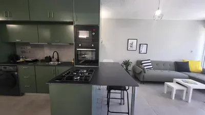 a kitchen and living room with green cabinets and a counter top at Hanapartment 3 bed Ayia NAPA in Ayia Napa