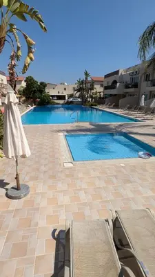 an empty swimming pool with an umbrella and a table at Pool flat near Ayia Napa in Sotira