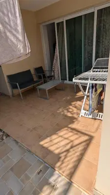 a screened in porch with a couch and a table at Pool flat near Ayia Napa in Sotira