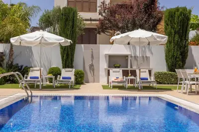 a swimming pool with two umbrellas and chairs and a table and a table at Ayia Napa Luxury Seaside Villa Ionion H15 in Ayia Napa