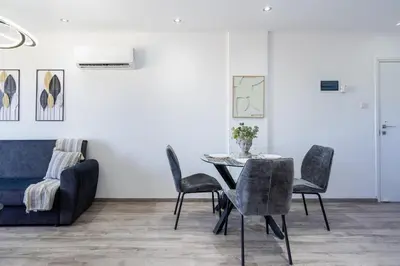 a dining room with a table and chairs and a couch at Olympus Stylish 2-BR Apt & Balcony in Larnaca in Larnaka