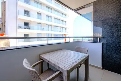 a table and chairs on a balcony with a building at Downtown Finikoudes Beach Apartment in Larnaka