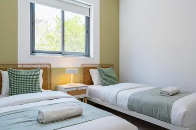 two beds in a room with a window at Solenne - Stylish 2-BR Apartment & Balcony in Larnaca in Larnaka
