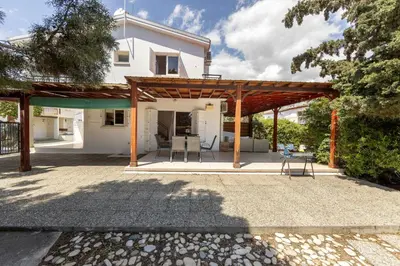 a patio with a wooden pergola in front of a house at Larnaca Seaside Villa Marina 44 in Pervolia