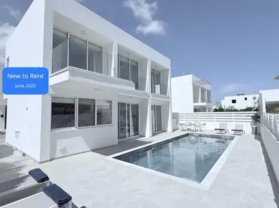 a large white building with a swimming pool in front of it at Bow Villa in Paralimni