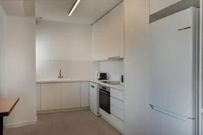 a white kitchen with white cabinets and a table at Phaedrus Living Travertine Residences 101 in Strovolos