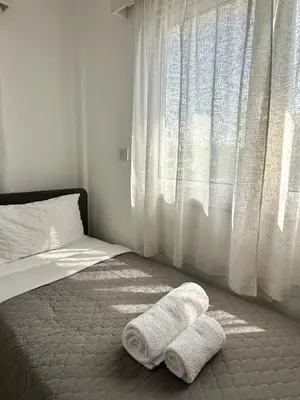 a bed with two towels on the floor next to a window at Sunrise Maisonette in Voroklini