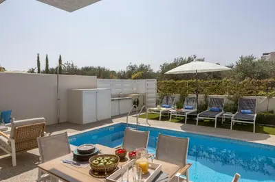 a patio with a table and chairs next to a pool at Milan's Mythical Villa in Paralimni