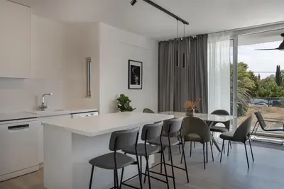 a white kitchen with a table and chairs at Phaedrus Living Travertine Residences 102 in Strovolos