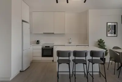 a kitchen with white cabinets and a table and chairs at Phaedrus Living Travertine Residences 102 in Strovolos