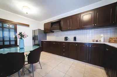 a kitchen with wooden cabinets and a table with a vase of flowers at Elite Seaside Apartment in Limassol