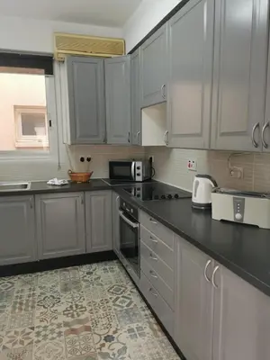 a kitchen with white cabinets and a black counter top at Anne 3 Bedroom Apartment in Larnaka