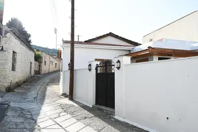 a white house with a black door on a street at ThemisHouse in Omodos