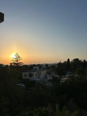 a sunset over a city with houses and trees at Modern 2BR Appartment near Finikoudes beach - Larnaka in Larnaka
