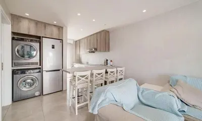 a kitchen with a table and a kitchen with a washing machine at Deluxe Apt - 500m Nissi Beach! in Ayia Napa