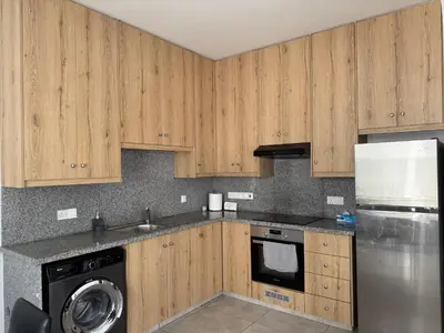 a kitchen with wooden cabinets and a dishwasher at Sun & Sea House in Paralimni