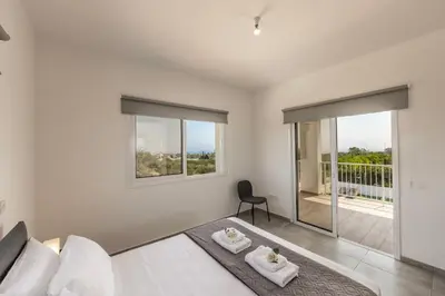 a white bedroom with a bed and a balcony at Ayia Napa Bay View Villa 6 in Ayia Napa