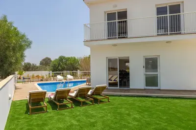 a house with a yard with chairs and a swimming pool at Ayia Napa Bay View Villa 6 in Ayia Napa