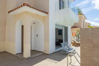 a patio with a chair and a building at Protaras El Sol Villa in Protaras