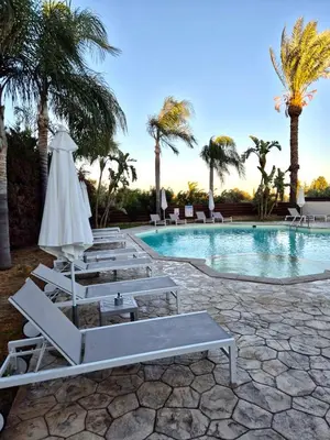 a pool with lounge chairs and an umbrella and palm trees at Seasons Retreat with pool and gym-2BR in Voroklini