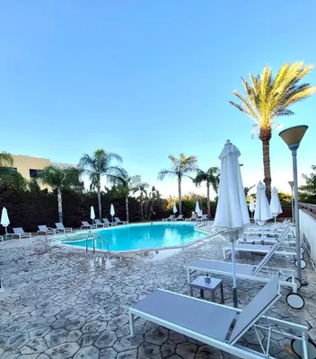 a pool with lounge chairs and a palm tree at Seasons Retreat with pool and gym-2BR in Voroklini