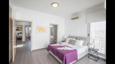 a white bedroom with a large bed with a purple blanket at Villa Prcv614, Luxury 6bdr Protaras Villa with Pool and Panoramic Sea views in Protaras