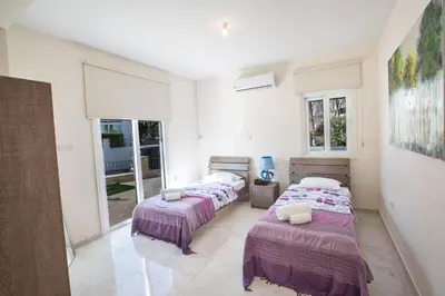 two beds in a white room with windows at Protaras Mesogeios Villa Me16 Beachfront Villa in Protaras Center in Protaras