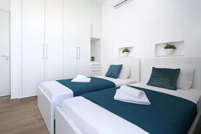 two beds in a white room with blue accents at MAREN - 250m from Golden Sandy Beach in Paralimni