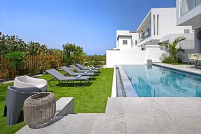 a pool with lounge chairs next to a house at MAREN - 250m from Golden Sandy Beach in Paralimni