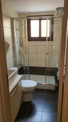 a bathroom with a toilet and a glass shower at Lovely ground floor apartment with BBQ in Aglantzia