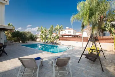 a pool with two chairs and a ladder next to it at Ayia Napa Holiday Villa At26 in Ayia Napa