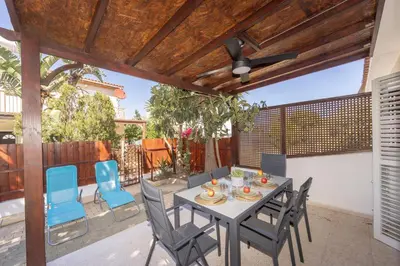 a patio with a table and chairs and a ceiling fan at Laranca Oneiro Seaside Villa in Pervolia
