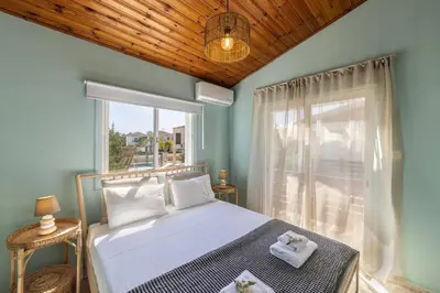 a bedroom with a bed and a large window at Laranca Oneiro Seaside Villa in Pervolia