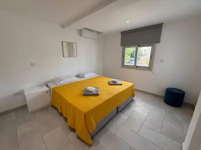 a room with a bed with a yellow blanket on it at Ayia Napa 2BR - Prime Location in Ayia Napa