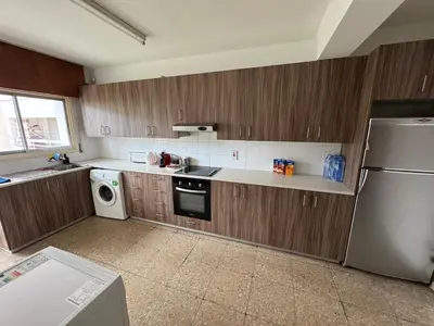 a kitchen with wooden cabinets and a stainless steel refrigerator at River Court, Flat 8 in Nicosia