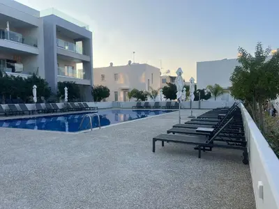 a row of lounge chairs next to a swimming pool at Modern Cosy Holiday Apartment in Paralimni