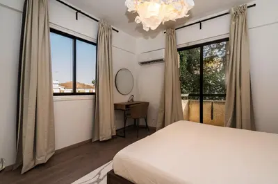 a bedroom with a bed and a desk and windows at City Centre Modern Boho Stay in Nicosia