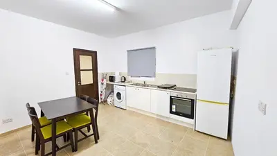 a kitchen with a table and a refrigerator at SKY Way City Apartment, 150m from Chabad Lubavitch in Larnaka