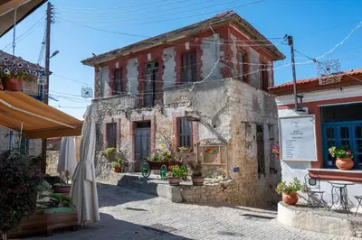 an old stone building with potted plants on a street at Traditional Stone House in Vouni, Quiet Stay with Courtyard & BBQ in Vouni