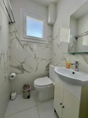 a white bathroom with a toilet and a sink at Lumière Retreat 2 in Larnaka