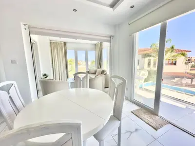 a white dining room with a white table and chairs at Lumière Retreat 2 in Larnaka