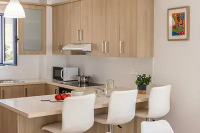 a kitchen with white chairs and a counter top at Protaras Seaside Villa Protamare 32 in Protaras