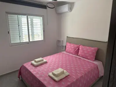 a bedroom with a pink bed with two towels on it at Near Finikoudes beach 1 in Larnaka