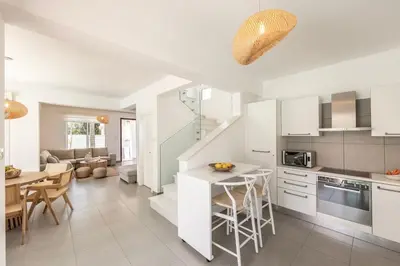 a kitchen with white cabinets and a table with chairs at SeaSalt Villa in Paralimni